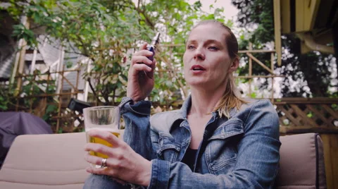 Woman vaping electronic cigarette while having glass of beer Stock Footage 64454435