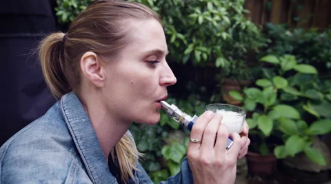 Woman vaping electronic cigarette while having glass of beer Stock Footage 64454487