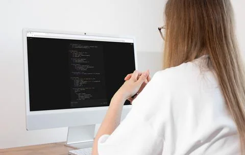 Woman vibe coding using dark mode AI assistant chatbot on computer monitor... Stock-Fotos