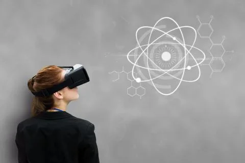 Woman in VR headset looking at interface against grey background Stock Photos