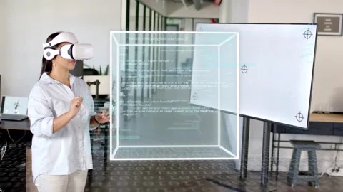 Woman in VR tapping controller and pointing, growing holographic cube with code, Stock Footage 334693797