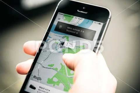 Woman waiting for the uber car on the street holding smartphone Stock Photos
