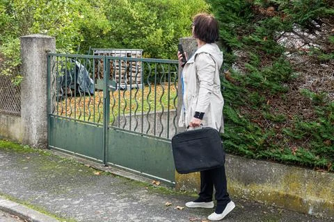 Woman waits at a gate while holding a phone and bag Stock Photos