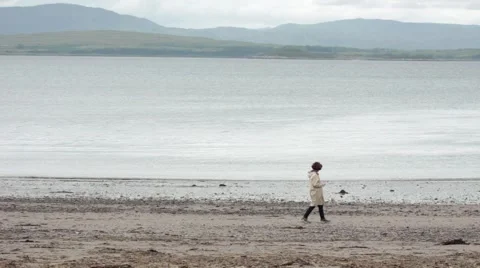 Woman Walking Across A Beach Stock Footage