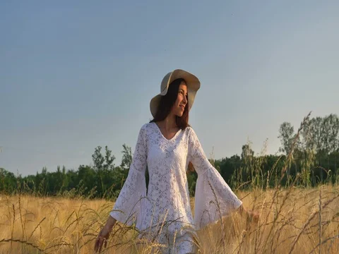 A woman is walking along a wheat field with a white dress Stock Footage