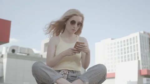Woman walking and using a smart phone in the street in a sunny summer day Stock Footage 134034664