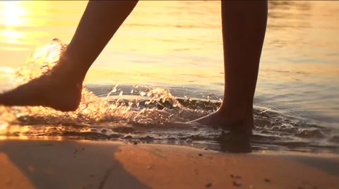 Woman walking on beach barefoot over sunset Stock Footage