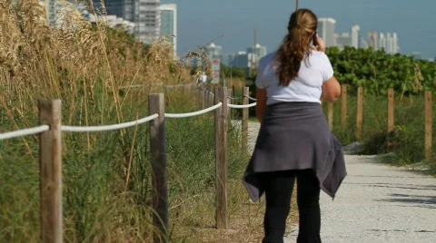 Woman Walking on beach, talking on cell phone Stock Footage