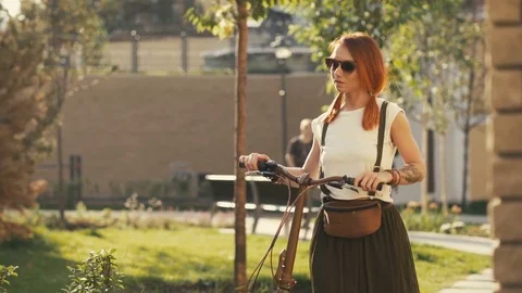 Woman walking beside riding bicycle on city park. Woman bike park Stock Footage