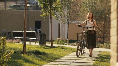 Woman walking beside riding bike in summer park. Woman bike park Stock Footage