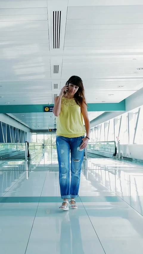 Woman walking between Automatic walkways, in subway crossing, using her phone, a Stock Footage 311318229