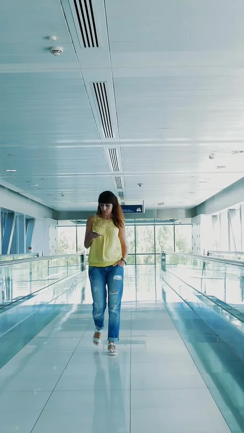 Woman walking between Automatic walkways, in subway crossing, using her phone, a Stock Footage 311319127