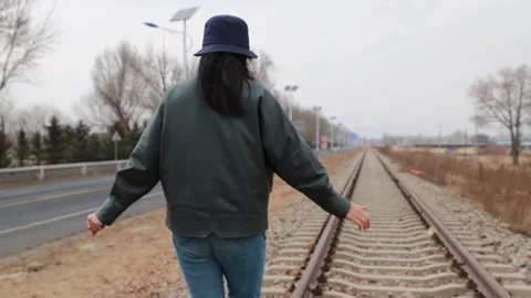 Woman walking directly forward on empty railway line Stock Footage 331721917