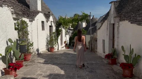 Woman Walking Down Flowered Trulli Street in Alberobello Puglia 스톡 동영상 337800296