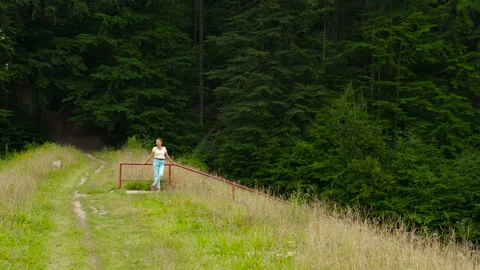 Woman walking down forest path stopping at intervals Stock Footage 301722094