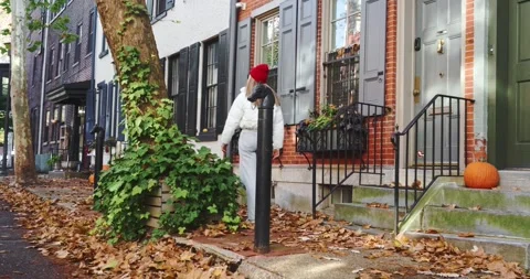 Woman Walking Down a Leaf-Covered Street in Autumn 스톡 동영상 325451283