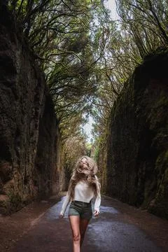 A woman is walking down a path in a forest Foto stock