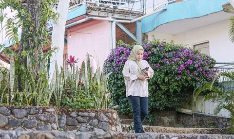A woman is walking down a path in front of a house with a dog Stock Photos