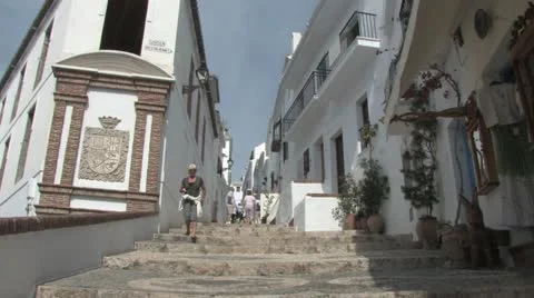 Woman walking down the steps between white washed buildings in Andalucia Spain Видео 11900012