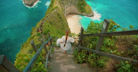 Woman walking down steps overlooking spectacular tropical coastal bay at Stock Footage 344213104