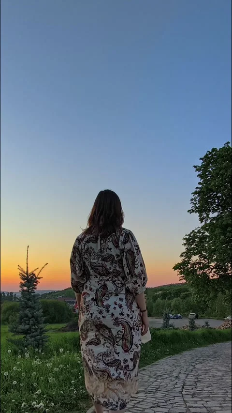 Woman walking down a stone path during a vibrant sunset Stock Footage 334556997