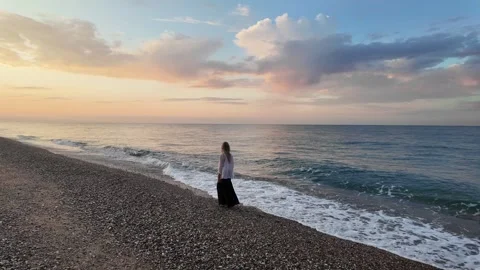 Woman walking on an empty beach during sunrise, amazing sea view background, 4K Stock Footage 277110760
