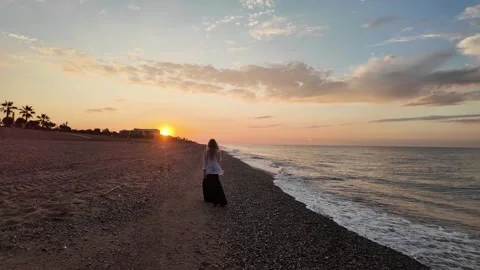 Woman walking on an empty beach during sunrise, amazing sea view background, 4K Stock Footage 277110761