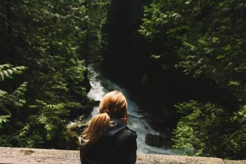 Woman walking on empty path through green forest Stock-Fotos