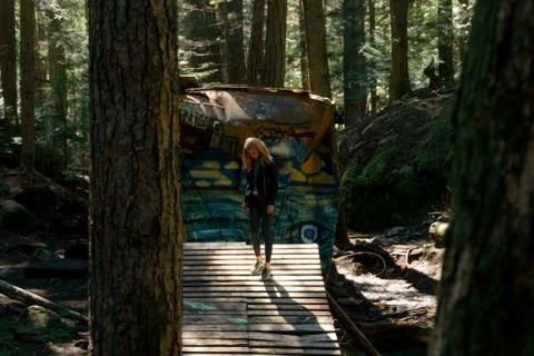 Woman walking on empty path through green forest Stock Photos