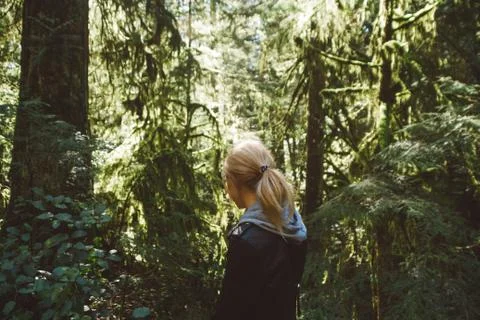 Woman walking on empty path through green forest Stock Photos