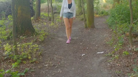 A woman is walking on a forest trail while wearing casual shorts Stock Footage 318924573