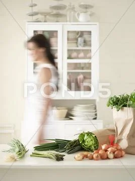 Woman Walking By Fresh Produce On Kitchen Counter Stock Photos