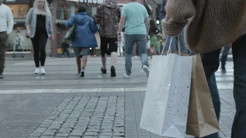 A woman walking at an intersection with multiple shopping bags. Видео 116505548