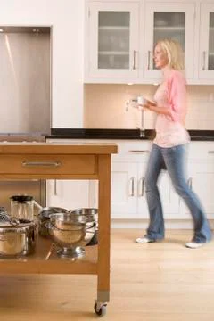 Woman walking in kitchen holding coffee Stock Photos