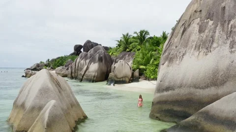 Woman walking in the ocean at Anse Source d'Argent beach  Video stock 132550419