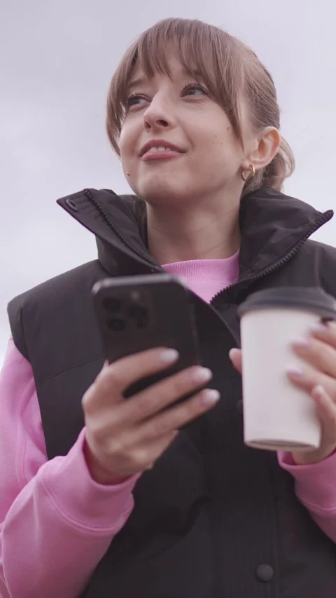 Woman walking in park using smartphone and drinking coffee Stock Footage 313299911