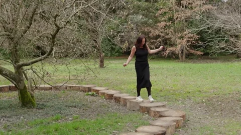 Woman walking on a path made of tree trunks in a park Stock Footage 320263483