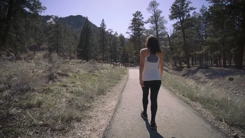 Woman walking on path in mountains surrounded by pine trees Stock Footage 74614280