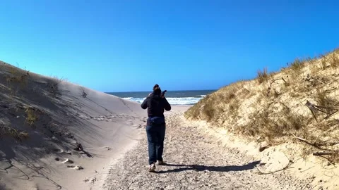 Woman walking on a sandy path toward the sea in Denmark Video stock 339434690