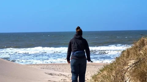 Woman walking on a sandy path towards the sea in Denmark Video stock 339434686