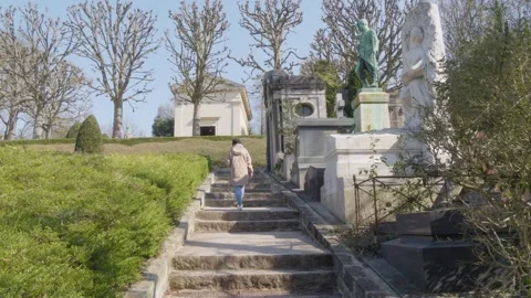 Woman walking up stone steps through Pere Lachaise Cemetery in Paris Video stock 337708530