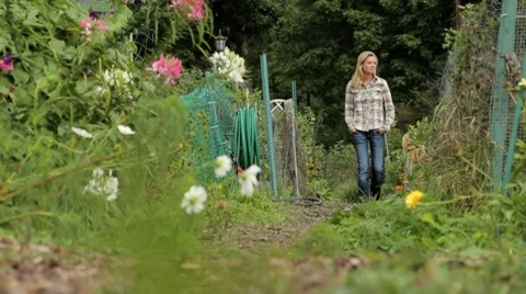 Woman walking through a community garden Stock Footage