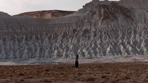 Woman walking through a dramatic desert canyon landscape Stock Footage 322020059