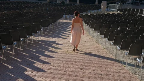 Woman walking through empty chairs in open air venue Stock Footage 334746581