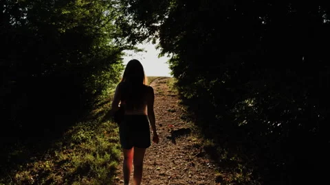 Woman Walking Through Forest Path Toward Bright Sunlight Stock Footage 339413011