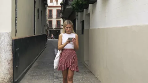 A woman walking towards camera, checking her phone and celebrating good news. Stock Footage 204014298