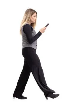 Woman walking while using a smartphone with long hair and casual clothes in a Stock Photos