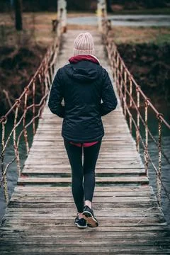 Woman walks across broken wooden bridge Stock Photos
