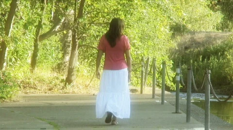 Woman walks by river back Stock Footage