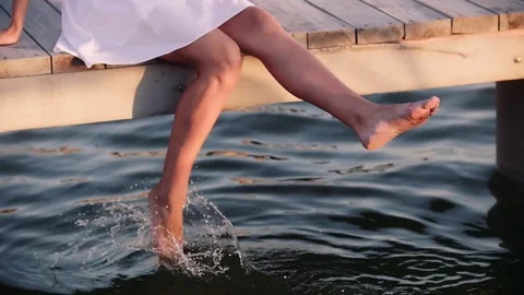 Woman walks on wooden pier in a summer day after jogging and dives into the Stock Footage